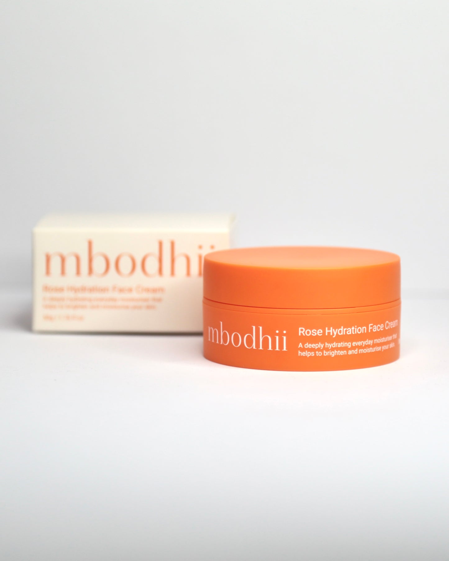 Orange mbodhii jar of Rose Hydration FAce Cream and white box on a white background